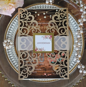 Intricate laser-cut gold glitter wedding invitation with floral patterns and wood texture