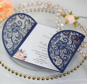 Macro detail of navy blue laser-cut lace invitation card with elegant floral inner page