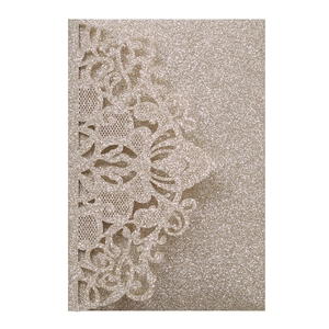 Detail of laser-cut lace champagne gold invitation with glitter finish and floral pattern