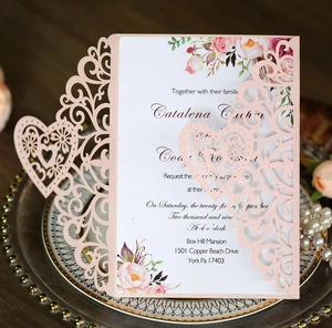Close-up of laser-cut heart pattern wedding invitation with floral printed inner card