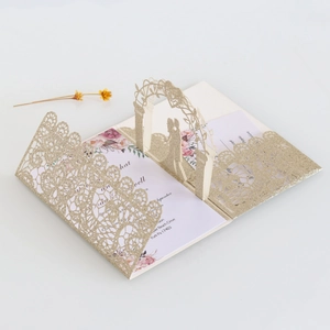Macro view of 3D pop-up wedding invitation with laser-cut lace and gold glitter