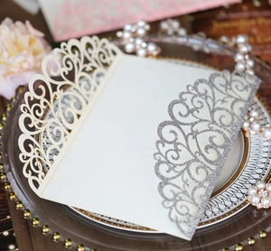 Detail of silver glitter laser-cut invitation on a decorative plate with pearls