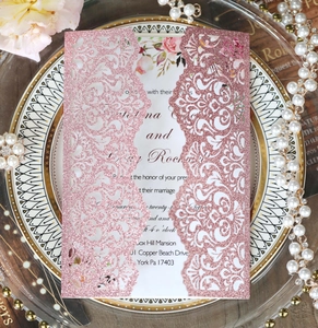 Detail of laser-cut rose gold glitter wedding invitation with floral inner card