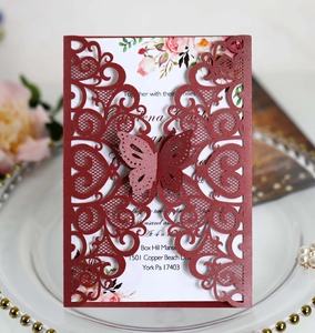 Detailed view of burgundy laser-cut wedding invitations with floral inserts and butterfly