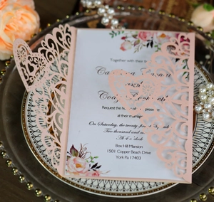Detail of pink laser-cut lace wedding invitation with elegant floral inner page design