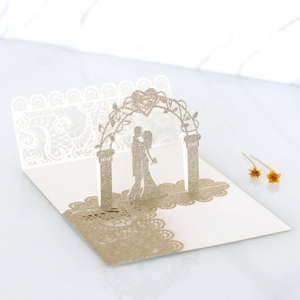 Macro shot of 3D pop-up wedding invitation featuring laser-cut arch and kissing couple