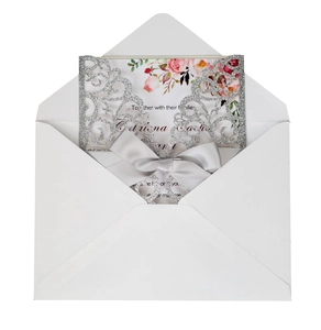 Detailed laser-cut silver glitter wedding invitation with grey satin bow and white envelope