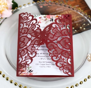 Close-up of laser-cut burgundy wedding invitation with elegant butterfly lace details