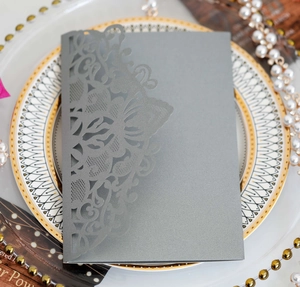 Macro view of grey laser-cut lace invitation cover with elegant pearl paper texture
