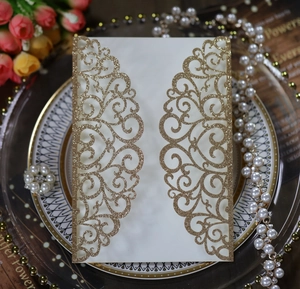 Detail of laser-cut wedding invitation cover with gold glitter scrolling patterns