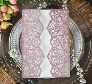 Detail of pink glitter laser-cut wedding invitation with hollow floral patterns and textures