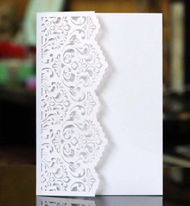 Detailed laser-cut white wedding invitation with intricate floral patterns on pearlescent paper