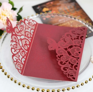 Detail of laser-cut butterfly lace patterns on wine red wedding invitation covers