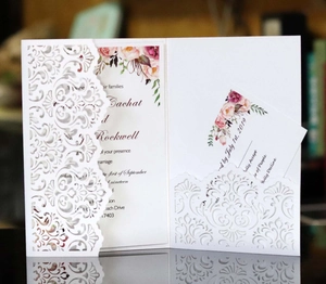 Elegant laser cut wedding invitation set with floral liner and RSVP card on reflective surface