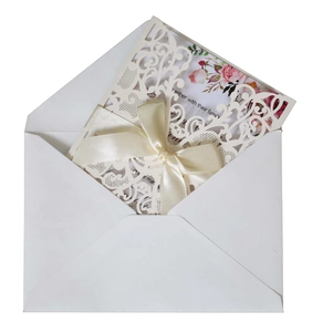 Detail of laser-cut floral wedding invitation with cream lace cover and silk bow