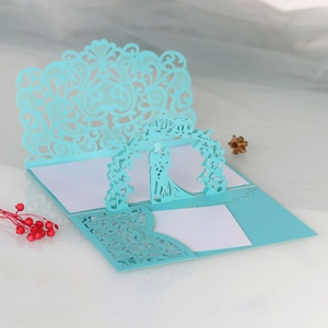 Détail d'invitation de mariage découpée au laser avec un couple 3D sous une arche fleurie
