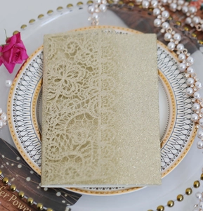 Detail of laser-cut lace floral pattern on glitter gold wedding invitation cover