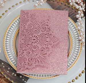 Dettaglio dell'invito di nozze rosa glitterato con motivo mandala tagliato al laser