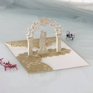 Gros plan d'une carte de mariage 3D découpée au laser avec paillettes dorées et mariés