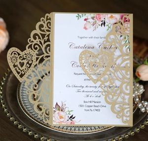 Detail of laser-cut heart pattern on gold pearlescent wedding invitation with floral insert