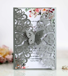Macro detail of laser-cut wedding invitation with butterfly buckle and floral inner card