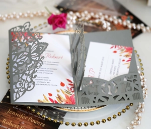 Macro view of laser-cut wedding invitation with intricate floral patterns and autumn leaf RSVP