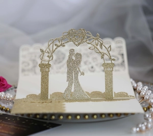 Detail of 3D laser cut wedding invitation with gold glitter finish and couple silhouette