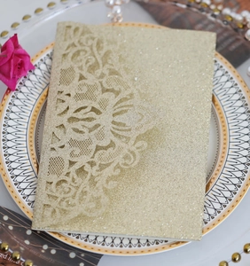 Détail de l'invitation de mariage en papier doré scintillant avec dentelle découpée