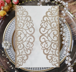 Detailed laser-cut wedding invitation with gold glitter floral patterns and pearls