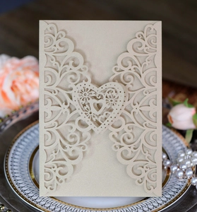 Detail of laser-cut champagne gold wedding card with floral patterns and heart motif