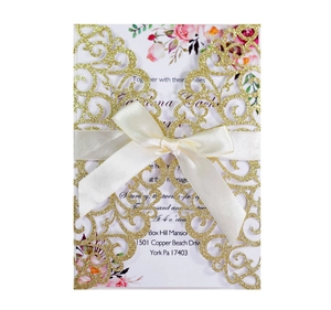 Detail of laser-cut glitter wedding invitation with elegant white satin bow accent
