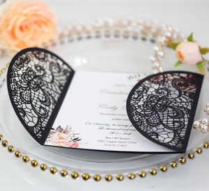 Close-up of black laser cut lace wedding invitation with elegant floral inner card