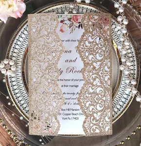 Macro shot of laser-cut glitter wedding invitation with champagne gold floral patterns