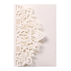 Macro detail of laser-cut floral patterns on elegant white wedding invitation cards