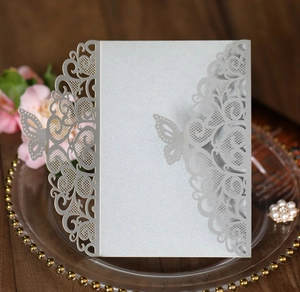 Detail of silver laser-cut wedding invitation with butterfly design and lace patterns