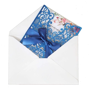 Detailed laser-cut navy blue wedding invitation with silk bow and floral insert card