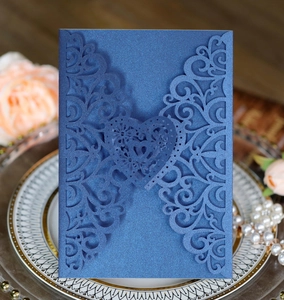 Macro detail of laser-cut navy blue heart invitation with pearlescent floral pattern
