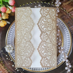Macro view of laser-cut glitter gold wedding invitation with intricate floral hollow design