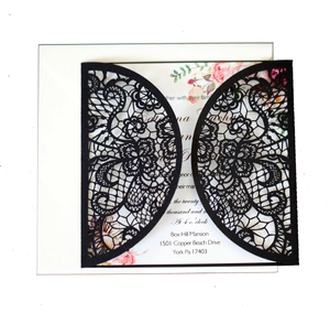 Close-up of laser-cut black lace wedding invitation with intricate floral inner card