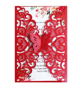 Detail of red laser-cut wedding invitation with hollow heart patterns and 3D butterfly decor