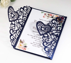 Detailed laser cut heart patterns on navy blue wedding invitation with white floral inserts