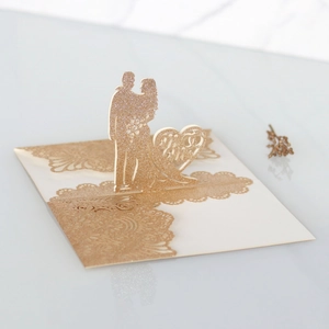 Dettaglio macro dell'invito di nozze 3D tagliato al laser con silhouette glitter oro