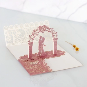 Detailed laser-cut 3D wedding invitation with pink glitter arch and lace silhouette
