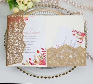 Close-up of gold glitter laser-cut wedding invitation with elegant floral RSVP card inserts