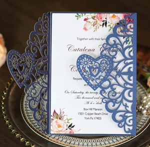 Detail of laser-cut heart floral lace wedding invitation on a decorative plate