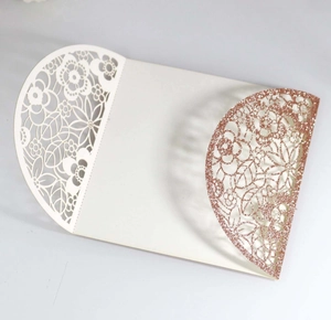 Detail of laser-cut floral pattern and rose gold glitter texture on wedding invitation