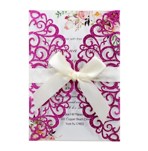 Detail of laser-cut wedding invitation with rose pink glitter and white satin bow