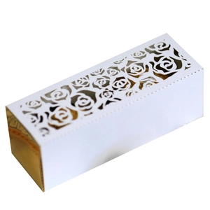 Detailed macro view of laser-cut white rose floral pattern on a gold-lined wedding box