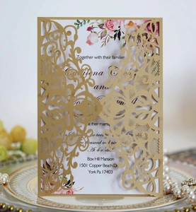 Macro shot of gold glitter laser-cut wedding invitation with pink floral inner card