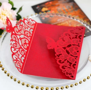 Macro detail of laser-cut red butterfly pattern on premium paper wedding invitation